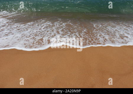 Azure onda con schiuma del mare su una spiaggia di sabbia. Il pittoresco paesaggio marino con acqua cristallina e sabbia gialla, colorato sfondo tropicale Foto Stock