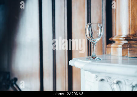 Wineglass vuota sul mantelpiece in un bellissimo interno Foto Stock