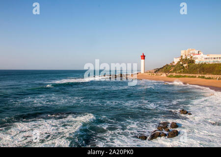 Il faro di umhlanga dominato da edifici con le onde che si infrangono sulle rocce Foto Stock