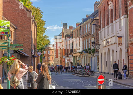 Una scena di strada in corrispondenza della giunzione di Lendal e Museo Street a York. Gli amanti dello shopping si mescolano in una palina ed edifici storici la linea street. Foto Stock