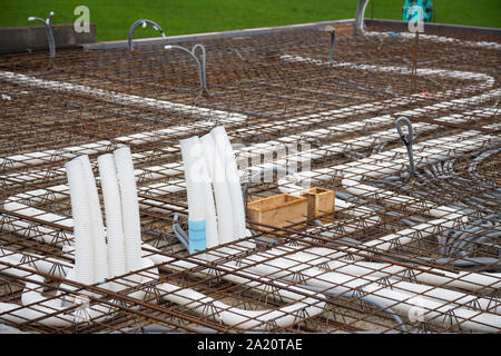 Sboccano i condotti di alimentazione e controllata di ventilazione interna su un soffitto in cemento in costruzione Foto Stock