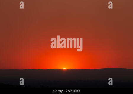 Smokey tramonto sul Gran Catena Divisoria, le particelle di fumo sono da incendi sono il blocco della luce provocando un rosso profondo cielo nebuloso. Foto Stock