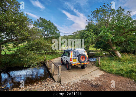 Auto attraversando ponte sopra un ruscello. Vicino Marsett, Yorkshire Dales National Park, Inghilterra. Foto Stock