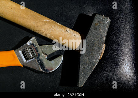 Vista superiore in prossimità di una chiave regolabile affiancati con un martello pesante su un materasso in pelle. la produttività, il concetto di lavoro di squadra. Foto Stock