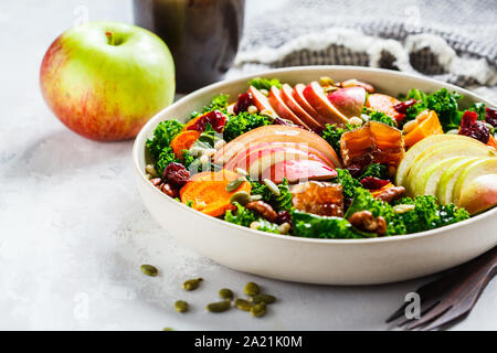 Insalata invernale con Apple, zucca, mirtilli rossi, il miele e i semi in una piastra bianca. Sano cibo vegan concetto. Foto Stock