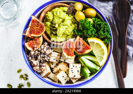 Ciotola di Buddha con la quinoa, tofu, kale, fichi e guacamole hummus in una piastra bianca. Foto Stock