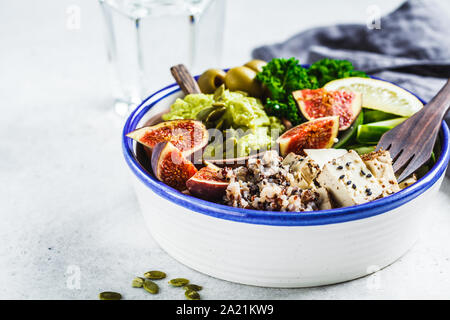 Ciotola di Buddha con la quinoa, tofu, kale, fichi e guacamole hummus in una piastra bianca. Foto Stock