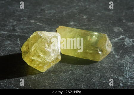 Gruppo di cristalli di apatite giallo-verde su sfondo grigio ardesia Foto Stock