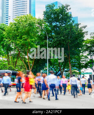 Paesaggio con la folla di gente di affari attraversamento strada nel centro cittadino di Singapore, il metropolis skyline in background Foto Stock