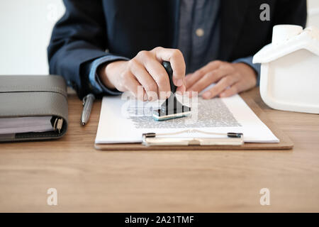 Real estate agent utilizzando stamper per la stampigliatura approvato il mutuo ipotecario contratto documento Foto Stock