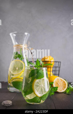 Infuso di acqua con limone e menta in vetro. Close up. Una sana detox bevanda per la mattina. Foto Stock