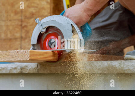 Nuovo home progetto constructiion imprenditore edile lavoratore utilizzando tenuto in mano unità worm sega circolare per il taglio di pannelli Foto Stock
