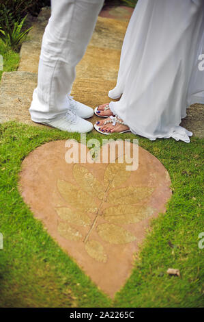 Primo piano dei piedi di sposa e sposo in piedi su erba verde Foto Stock