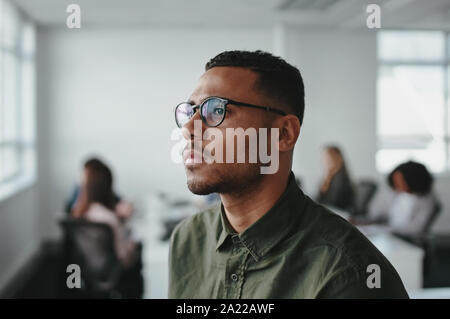 Close-up di un giovane americano africano business man imprenditore indossando occhiali contemplando in ufficio Foto Stock
