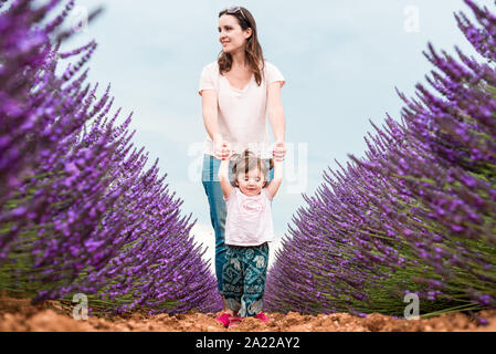 Felice madre e figlia a passeggio tra i campi di lavanda in estate Foto Stock