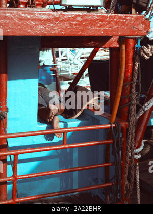 Uomo dorme in barca nel porto di pescatori, Bali, Indonesia Foto Stock