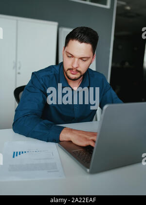 Business man analizza i dati aziendali, occupato a lavorare sul computer portatile e business report sulla scrivania in ufficio Foto Stock