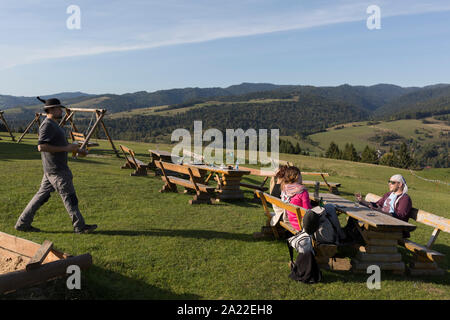 Un giovane Polo porta una birra al tavolo con gli amici godendo di panorami della montagna in tutta la valle, il 21 settembre 2019, in Jaworki, vicino Szczawnica, Malopolska, Polonia. Foto Stock