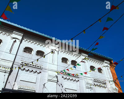 Festa colorati bandiere luminose bandiere di carta, lampadine luci appesa sopra il profondo blu del cielo e antico edificio di pietra di sfondo festival città di concetto Foto Stock