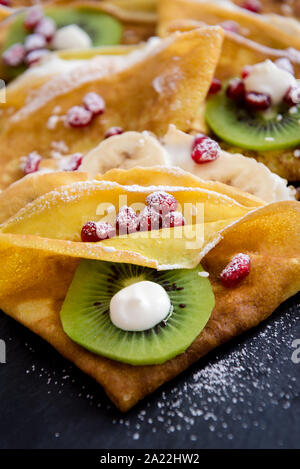 Crespelle sottili con il cioccolato fuso, i semi di sesamo, melograno e mandorle Foto Stock