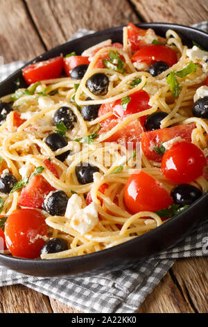 Pasta greca insalata di spaghetti con feta, le olive, i pomodori e le erbe close-up su una piastra sul piano verticale. Foto Stock