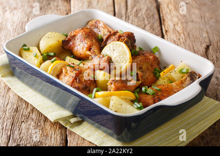 Gustose le cosce di pollo al forno con limone e patate bollite in salsa di aglio close-up in una teglia sul tavolo orizzontale. Foto Stock