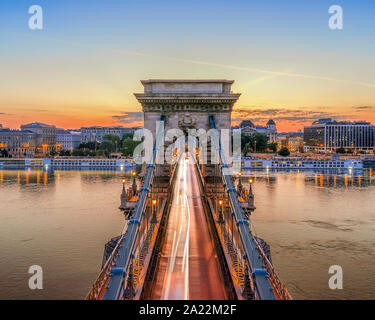 Il Ponte delle catene a Budapest, Ungheria. Fiume Danubio con barche. Traffico di sera con la luce dei sentieri. Paesaggio urbano dell'antenna. Foto Stock