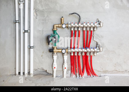 Pavimento radiante di Installazione sistema di riscaldamento. L'uomo installare sotto il pavimento per il riscaldamento di acqua di costruzione del pavimento. Riscaldamento a pavimento l'installazione. Foto Stock