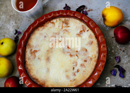 Home resa dolce torta di mele e la tazza di tè sulla texture di sfondo di calcestruzzo. Accogliente e sana colazione con frutta e bevanda calda Foto Stock