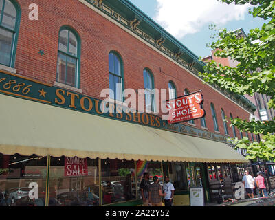 Persone che passeggiano passato la famosa Stout scarpa del negozio situato lungo Mass Ave, uno dei sei designati distretti culturali a Indianapolis, Indiana, STATI UNITI D'AMERICA Foto Stock