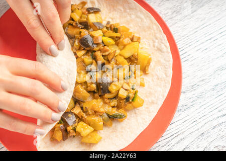 Ragazza preparare una rapida colazione a base di pane pita e cotto di melanzane e zucchine su una targhetta rossa. Tradizionale Turca e Armena, piatti Foto Stock