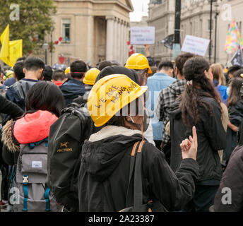 Protestor indossando maschera facciale e casco giallo recante la dicitura "Siamo Hong Kong" a dimostrazione contro la sovranità cinese di Hong Kong, Trafalgar Square, Londra, 28 settembre 2019. Centinaia di pf la gente si riunisce dopo marciando dal Consolato cinese Foto Stock