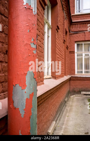 La grondaia con peeling di vernice sul vecchio edificio in mattoni Foto Stock