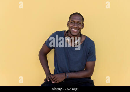 Ritratto di un uomo africano con cuffie di ridere sulla parete colorata Foto Stock