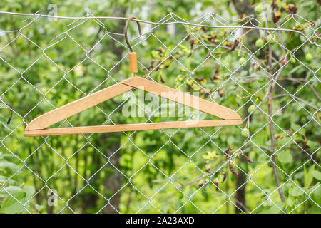 Staffe di metallo appeso su una recinzione metallica su uno sfondo di verdi in un villaggio Foto Stock