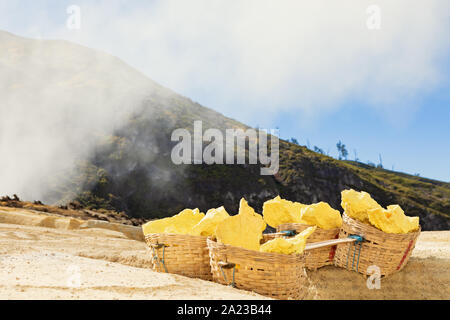 Cestello pesante laden da pezzi di zolfo naturale di trasportare dai minatori dal cratere miniera. Il lavoro manuale di zolfo operazione mineraria in Kawah Ijen volcano Foto Stock