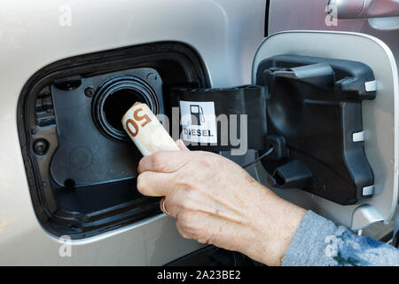 La mano di una donna di mettere le banconote in euro in un serbatoio per auto Foto Stock