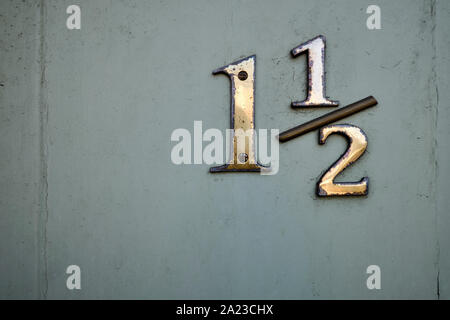 Chiusura del numero della porta fatta di opacizzato e scheggiato che mostra in ottone numero uno e una metà di un opaco porta verde Foto Stock