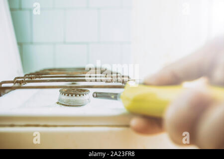 La mano si infiamma il bruciatore a gas, servendosi di un accendino in cucina di mattina Foto Stock