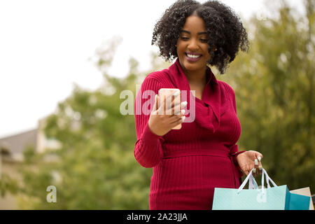 Bella americano africano donna shopping e i messaggi di testo. Foto Stock