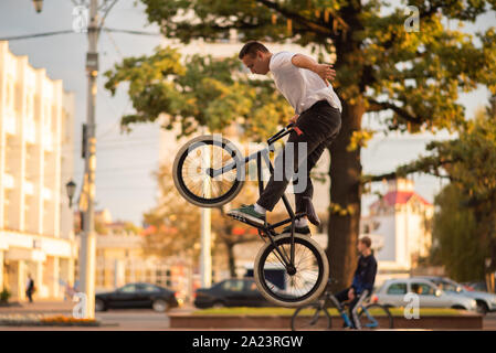 Il ragazzo esegue uno stunt sul BMX, saltando dal parapetto in alto. Foto Stock