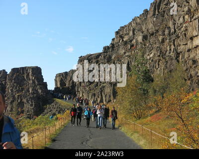 I turisti di seguire attraverso il sentiero attraverso la gola Almannagja a Thingvellir National Park, dove il North American & Eurasian placche tettoniche split. Foto Stock