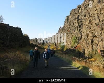 I turisti di seguire attraverso il sentiero attraverso la gola Almannagja a Thingvellir National Park, dove il North American & Eurasian placche tettoniche split. Foto Stock