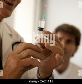 Vista ritagliata di un medico in possesso di una siringa nella sua mano. Foto Stock