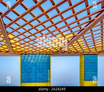 Giallo e blu spiaggia rifugio con apri Pannello di legno sul tetto di fronte ad un mare calmo. Da Muscat Oman. Foto Stock