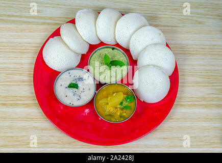 Idlis disposti in una formazione circolare con il bianco e il verde mostarde e sambar in una targhetta rossa. Foto Stock