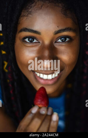 Giovane donna nera di mangiare una fragola, Cali, Colombia Foto Stock