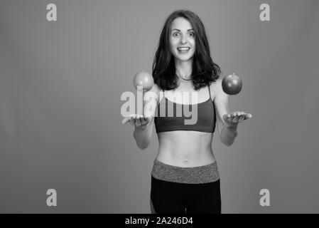 Giovane bella donna pronta per la palestra contro uno sfondo grigio Foto Stock