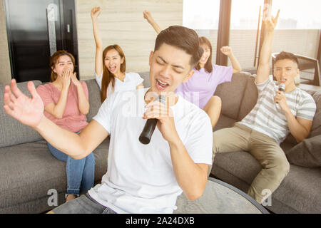 Gruppo di amici a giocare il karaoke a casa Foto Stock