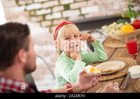 Ridendo figlia avente faccia sporca dopo aver mangiato le uova Foto Stock